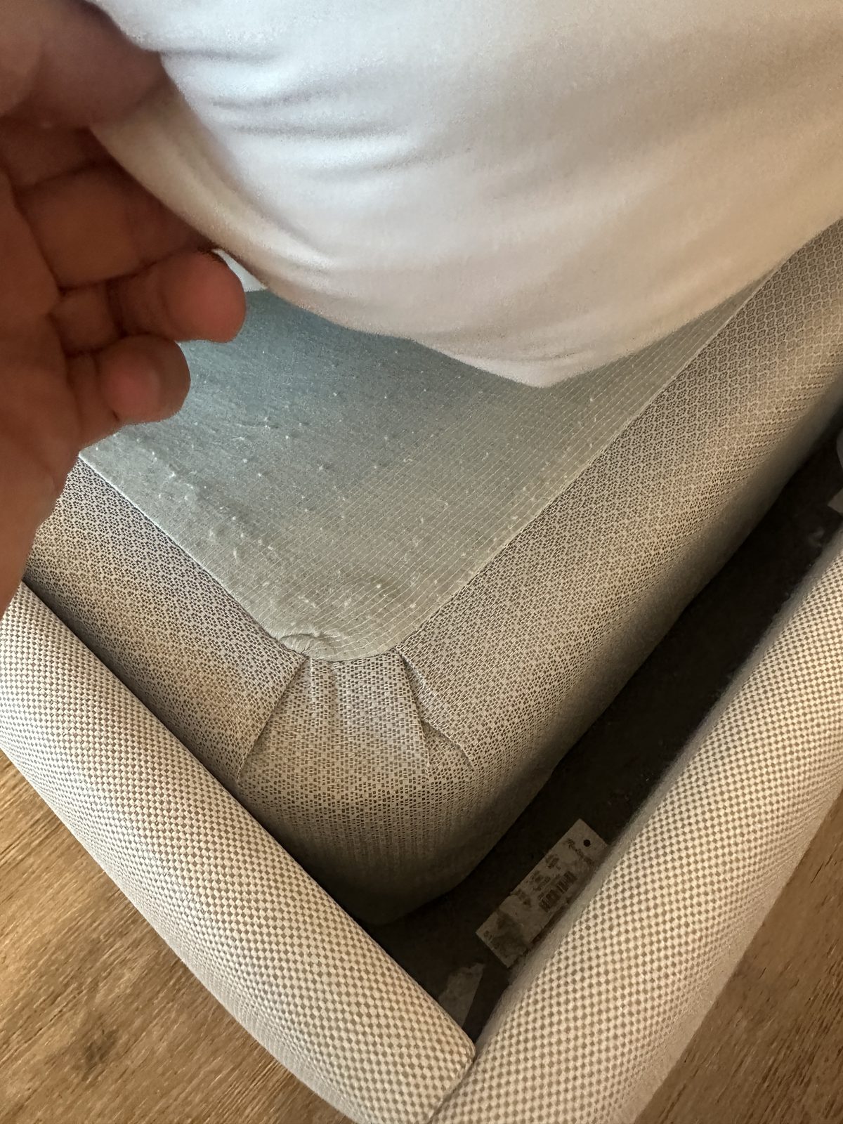 Lifting the corner of a hotel sheet to inspect the mattress seam and box spring for bed bugs